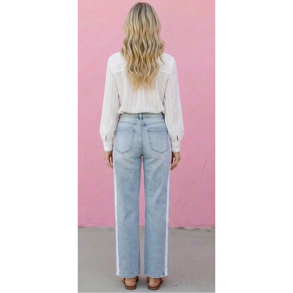 Person wearing light blue jeans and a white blouse against a pink wall