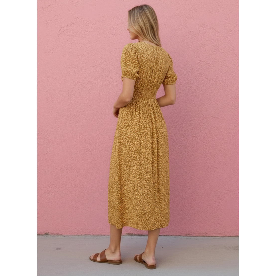Woman wearing a yellow dress against a pink wall
