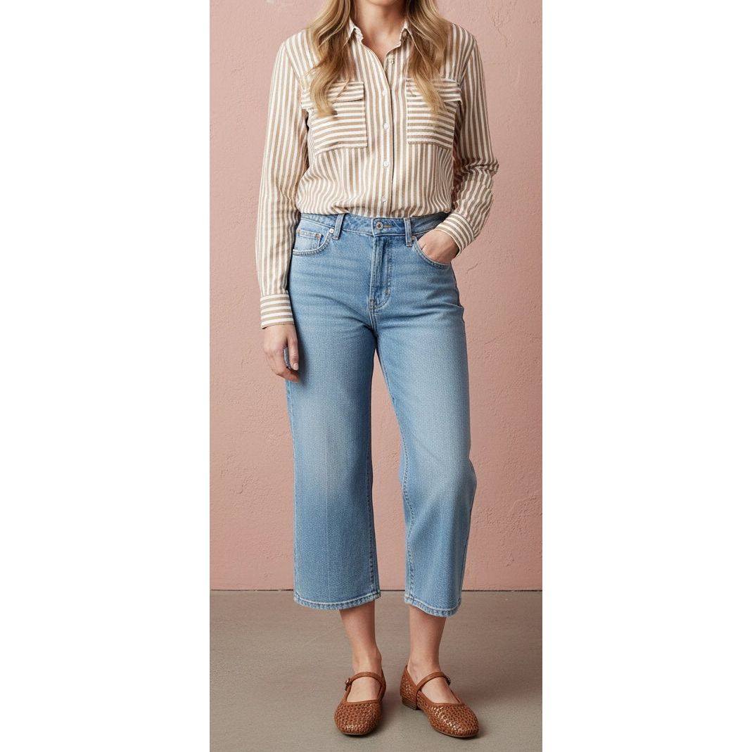 Woman wearing a striped shirt and blue jeans against a pink wall