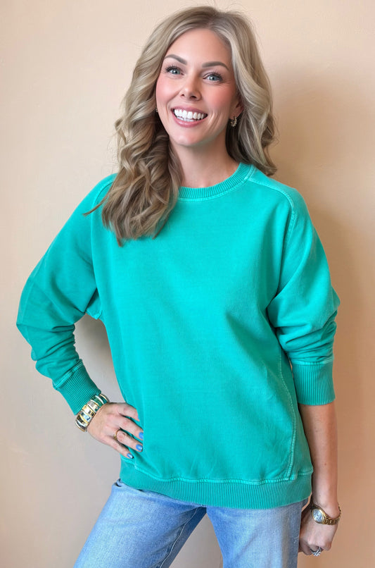 Woman wearing a teal sweater against a beige background