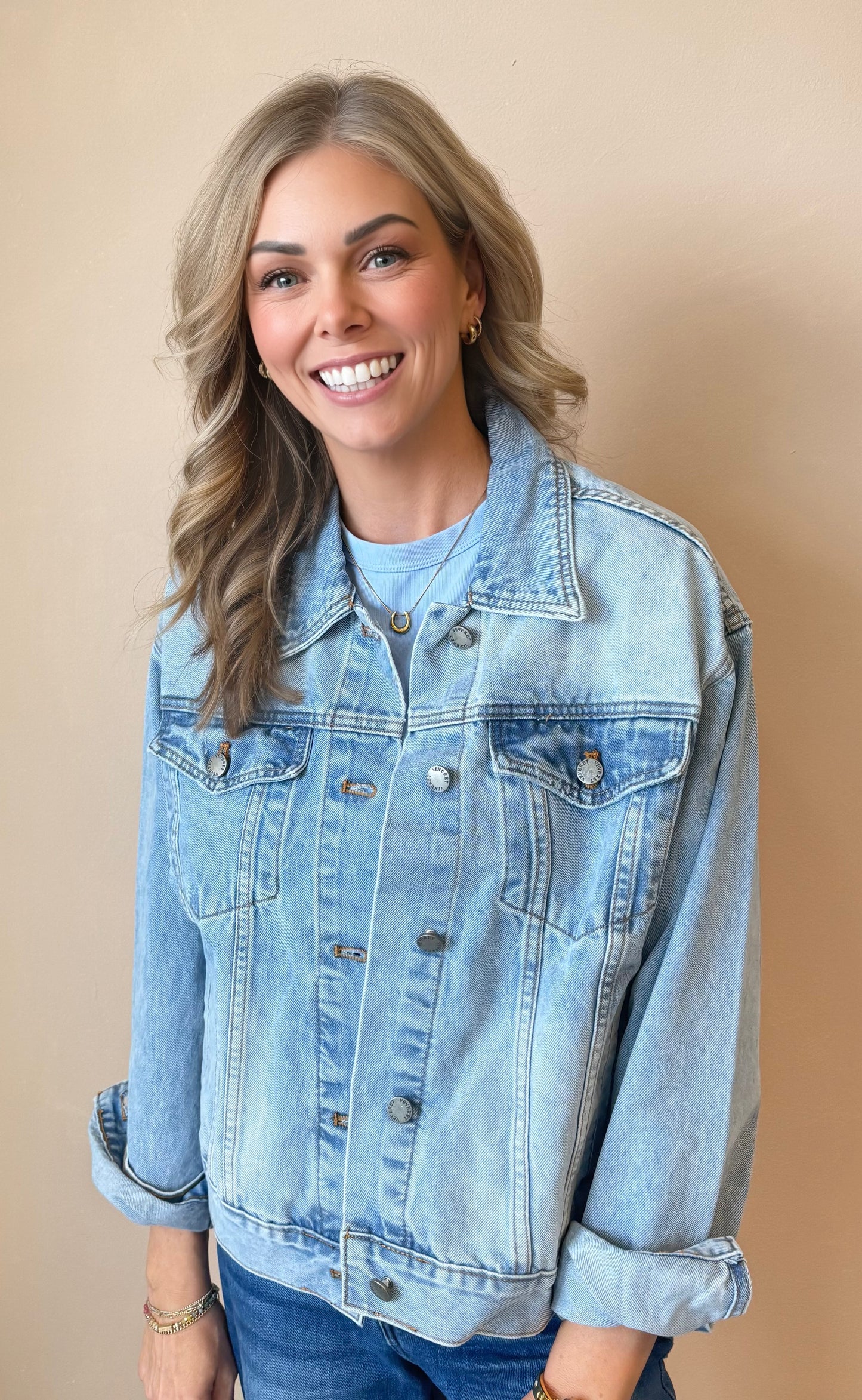 Woman wearing a light blue denim jacket against a beige background