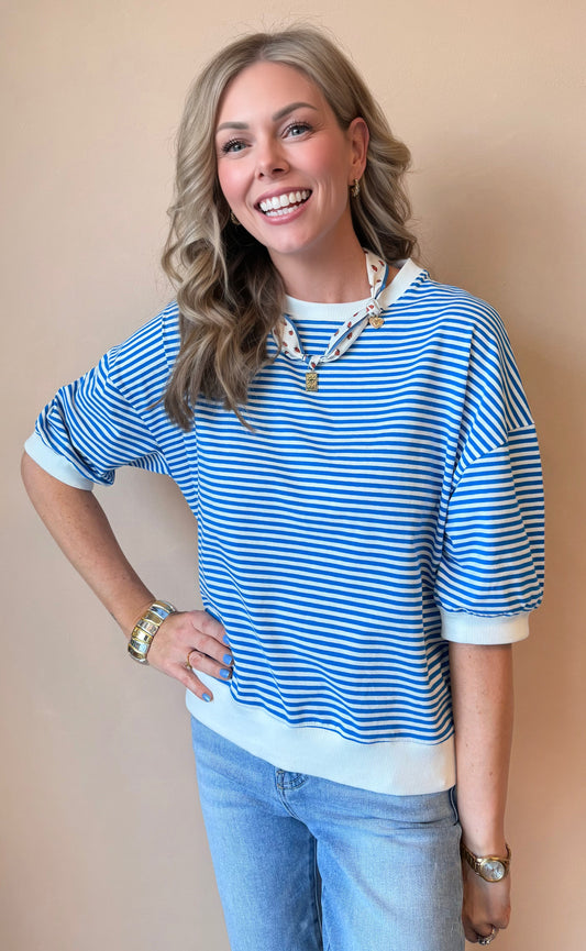 Woman wearing a blue and white striped shirt with a beige background