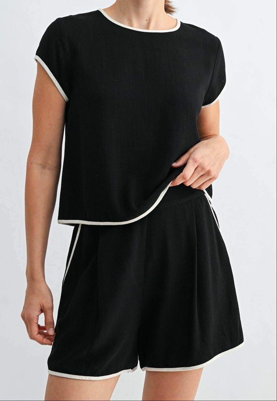 Woman wearing a black outfit with white trim on a light gray background
