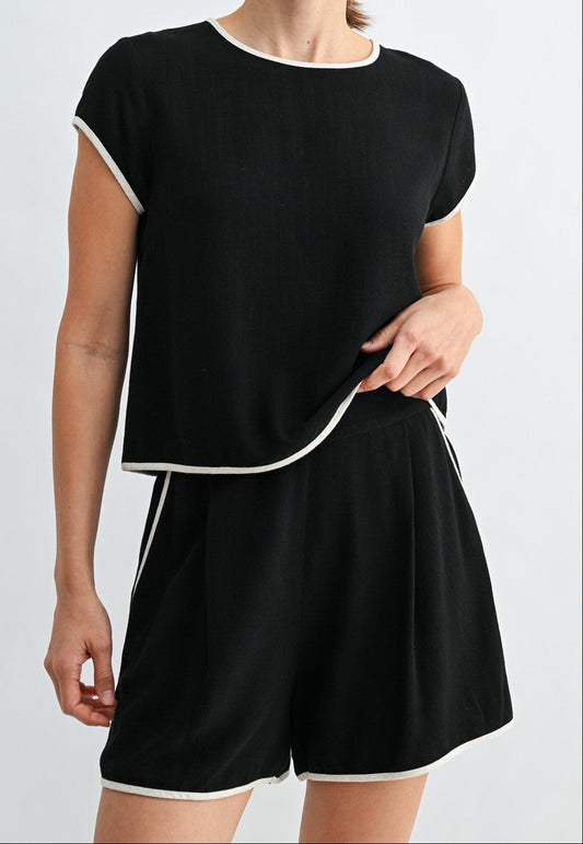 Woman wearing a black outfit with white trim on a light gray background