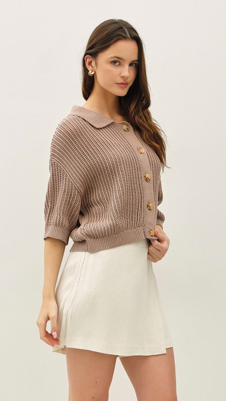 Woman wearing a brown sweater and white skirt on a plain background