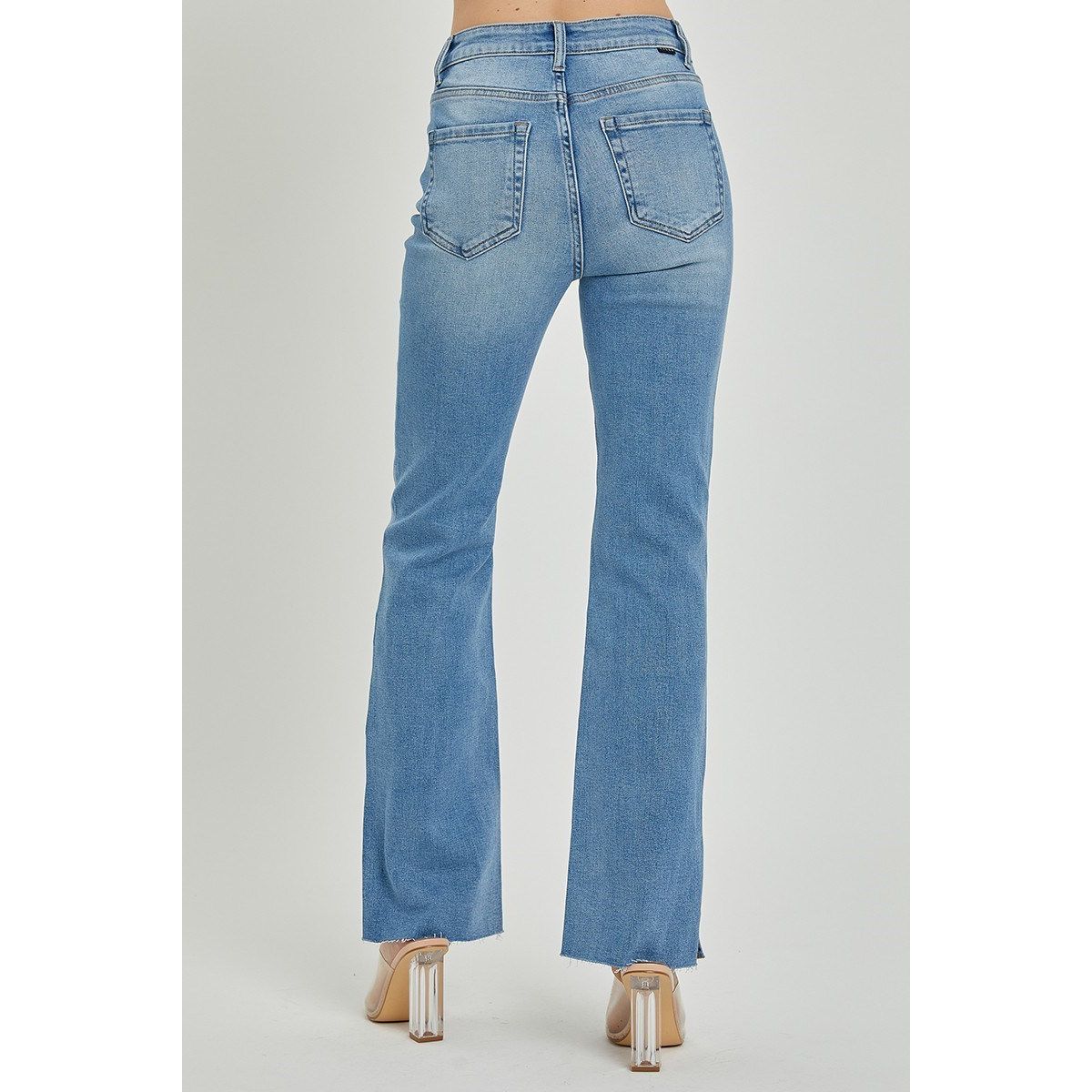 High rise bootcut blue jeans with raw cut hem and side slit detail on a gray background 