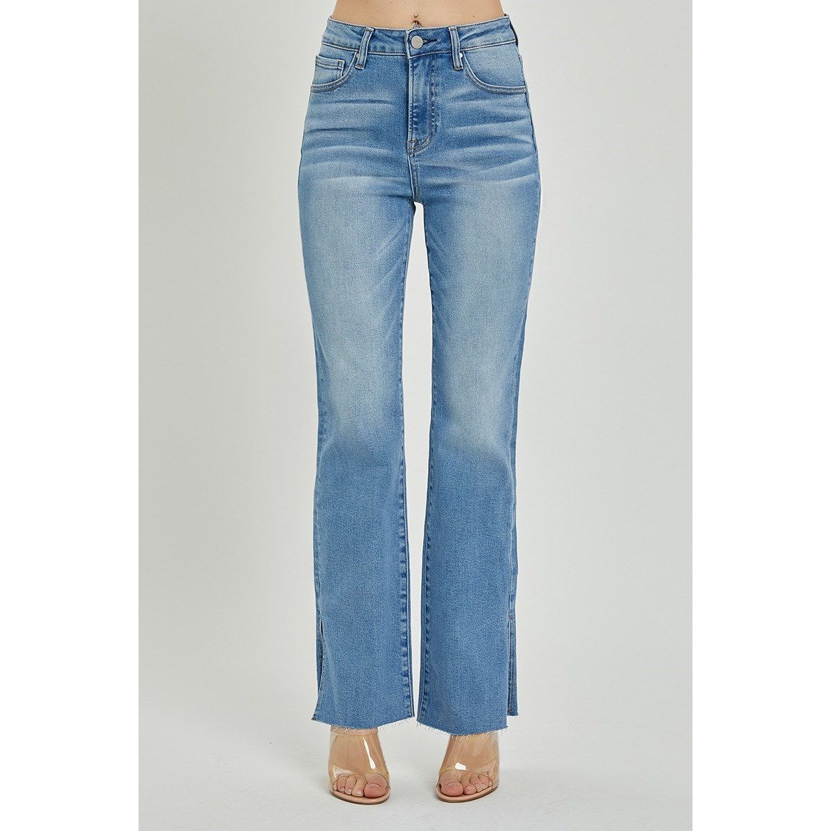 High rise bootcut blue jeans with raw cut hem and side slit detail on a gray background 