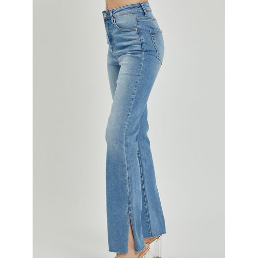High rise bootcut blue jeans with raw cut hem and side slit detail on a gray background