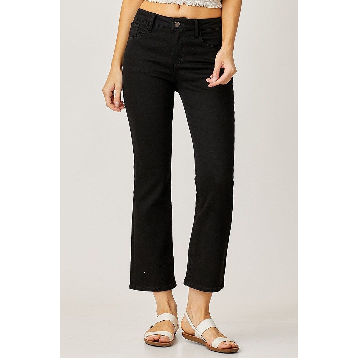 Person wearing black risen jean pants on a plain background