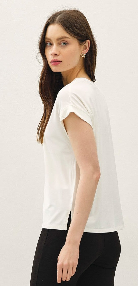 Woman wearing a white top and black pants on a light gray background