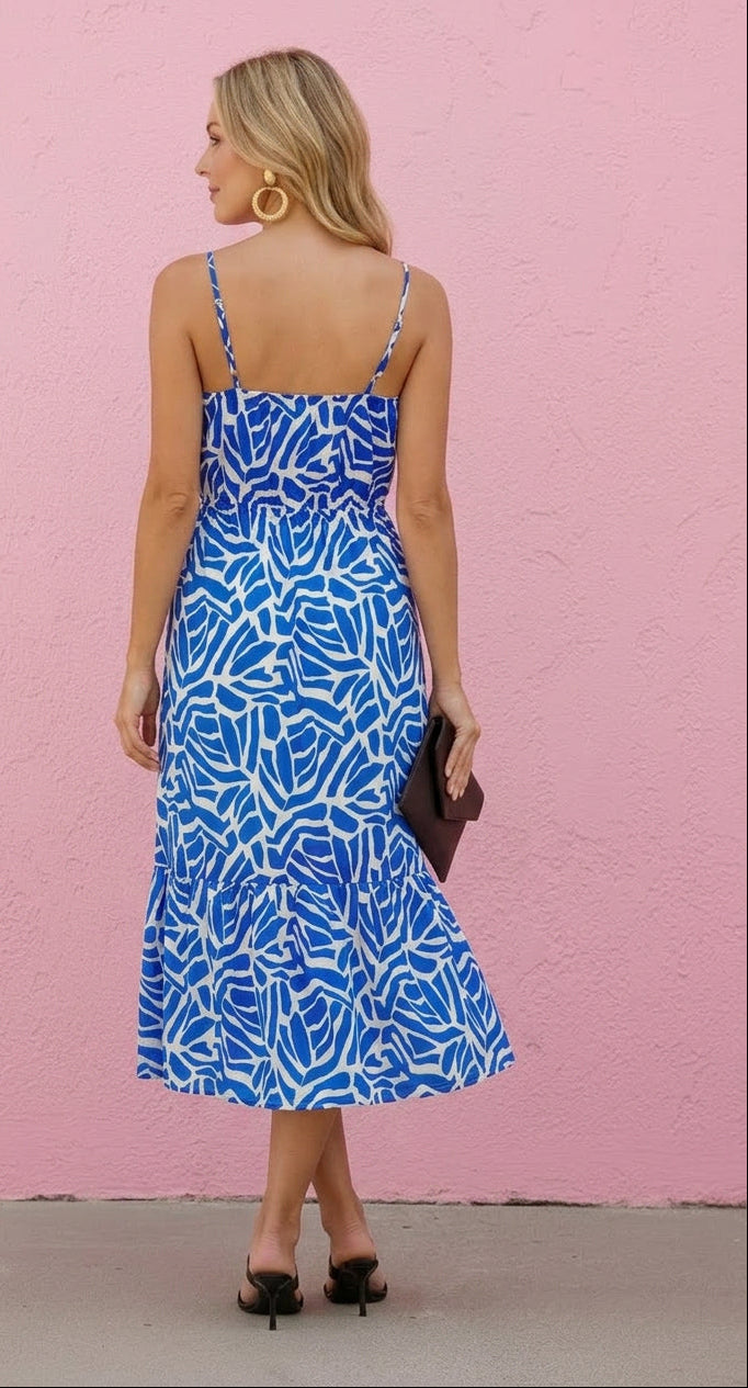 Woman wearing a blue patterned dress against a pink wall