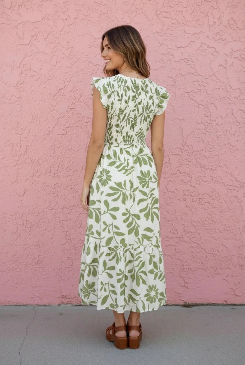 Woman wearing a green floral dress against a pink wall