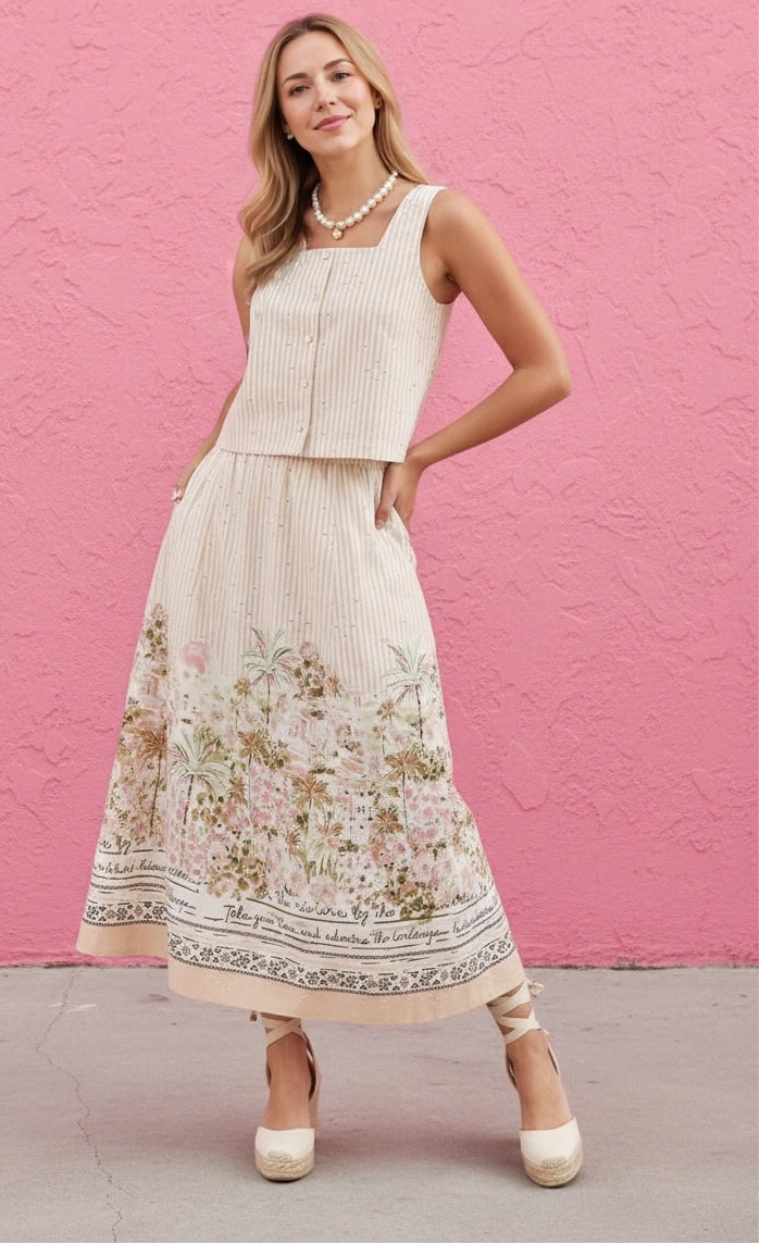 Woman wearing a white top and floral skirt against a pink wall