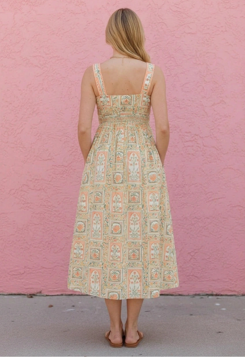 Woman wearing a patterned dress against a pink wall
