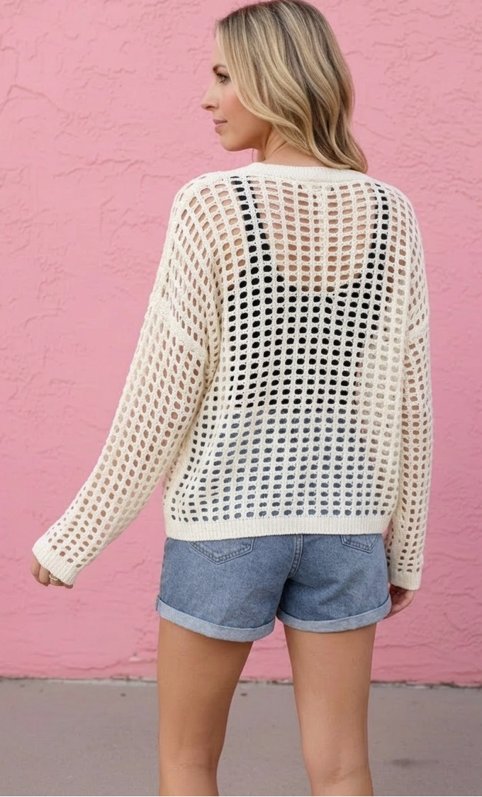 Woman wearing a white mesh top and denim shorts against a pink wall