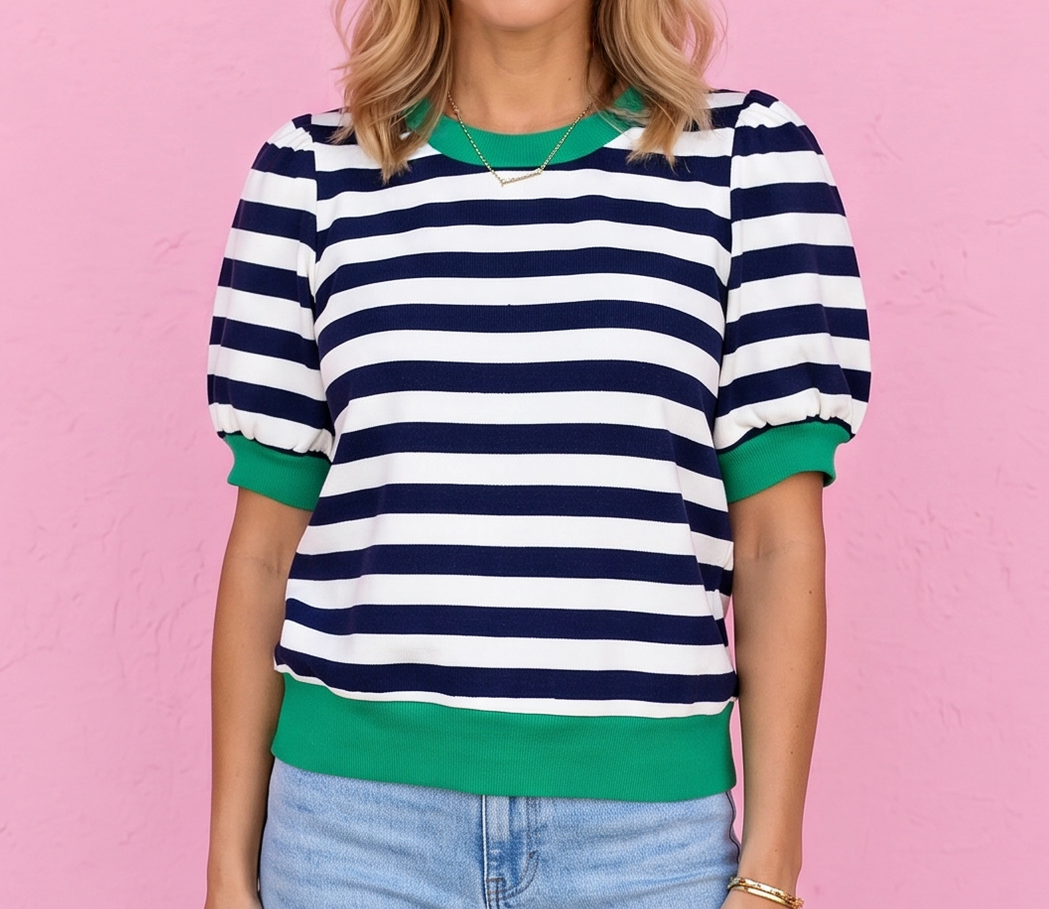 Woman wearing a striped shirt and jeans against a pink wall