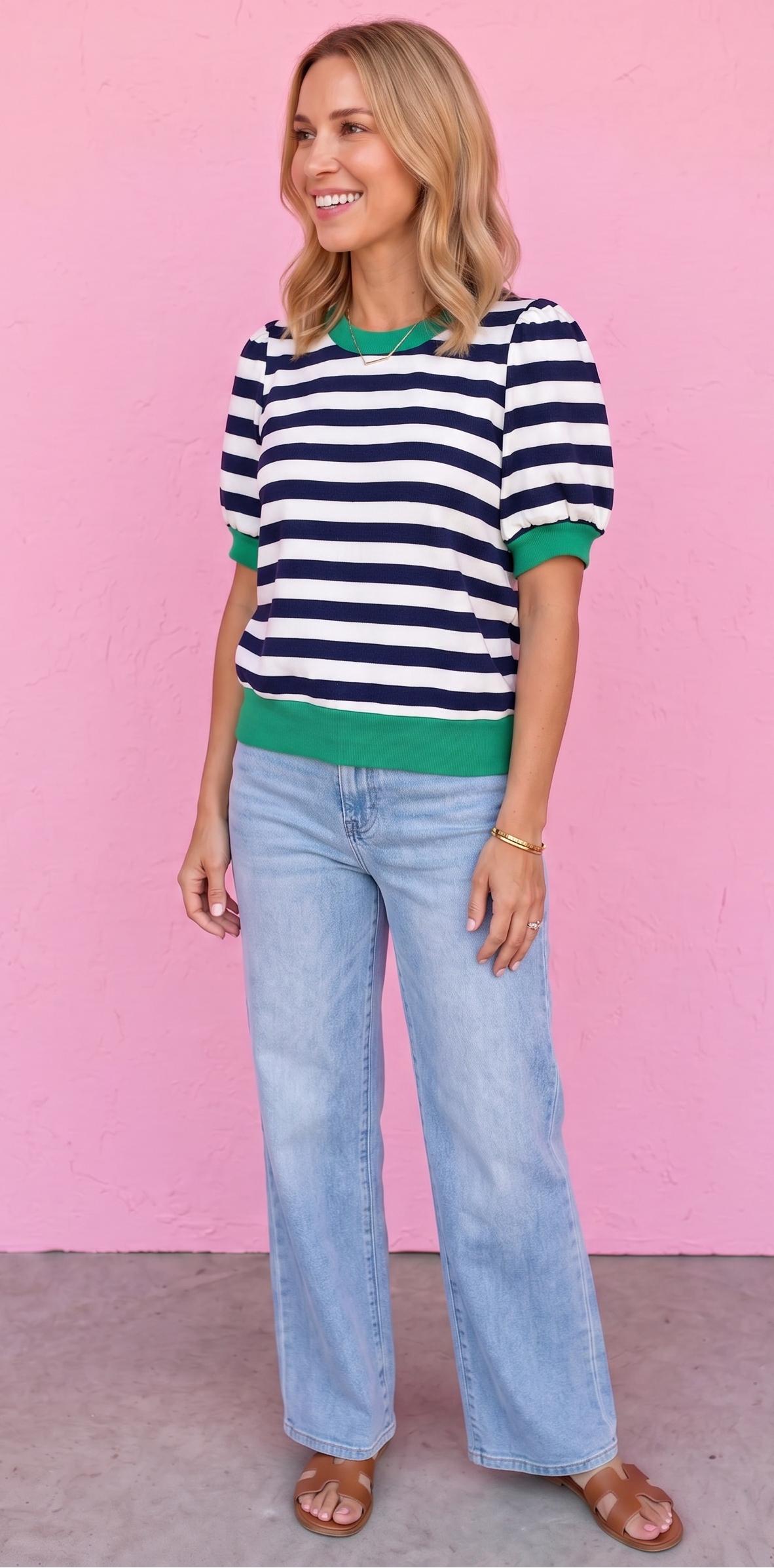 Woman wearing a striped sweater and jeans against a pink background
