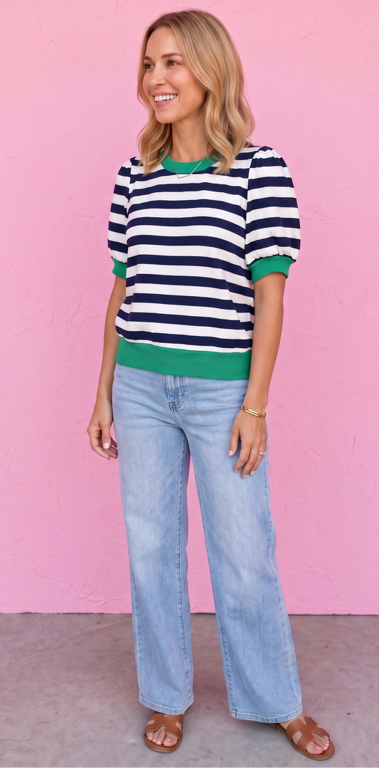 Woman wearing a striped sweater and jeans against a pink background