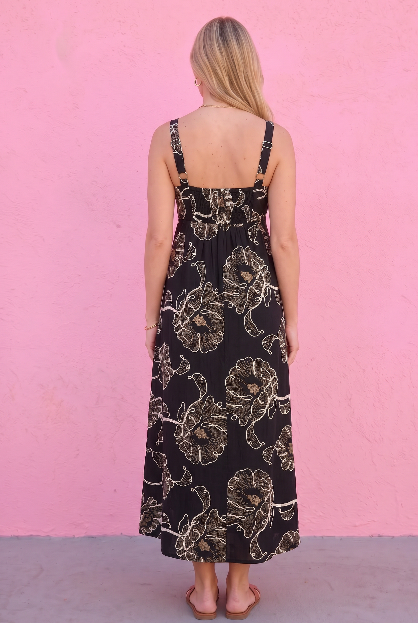 Woman wearing a black floral dress against a pink wall