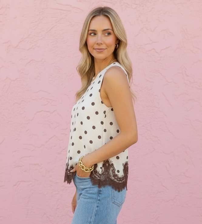 Woman wearing a polka dot top and blue jeans against a pink wall