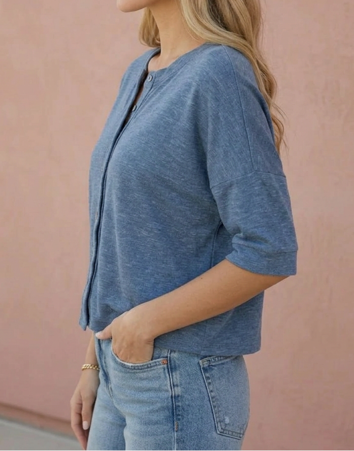 Woman wearing a blue top and jeans against a pink wall