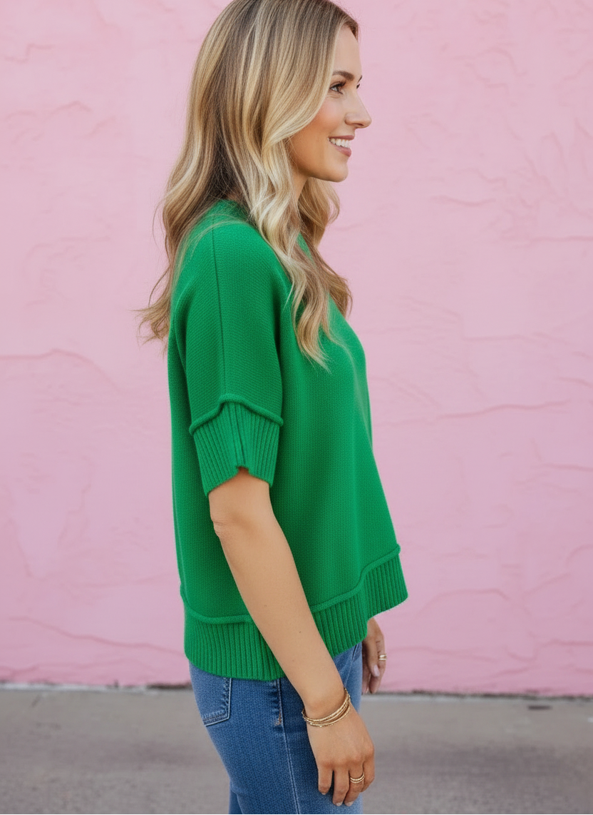 Woman wearing a green sweater against a pink wall