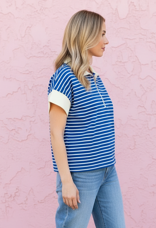Woman wearing a blue and white striped shirt and jeans against a pink wall.