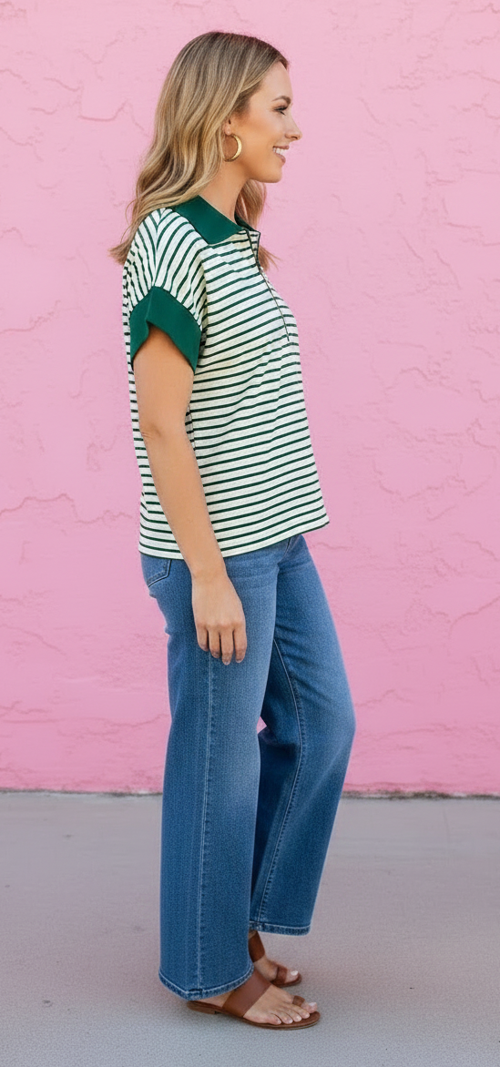 Woman wearing a striped shirt and jeans against a pink wall