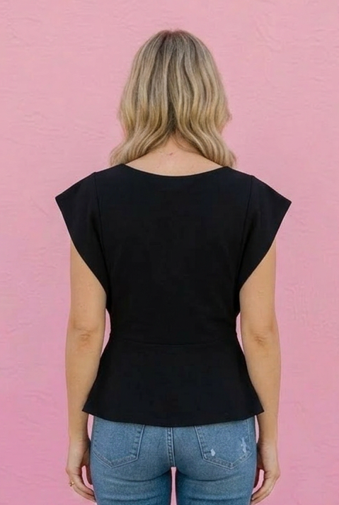Person wearing a black top and blue jeans against a pink wall