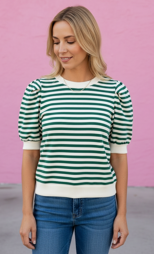 Woman wearing a green and white striped shirt against a pink background