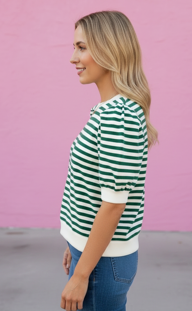 Woman wearing a green and white striped shirt against a pink background