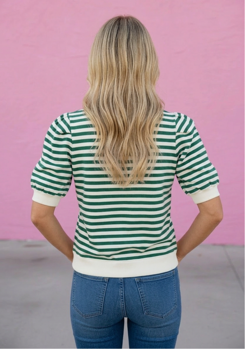 Person wearing a green and white striped shirt against a pink background