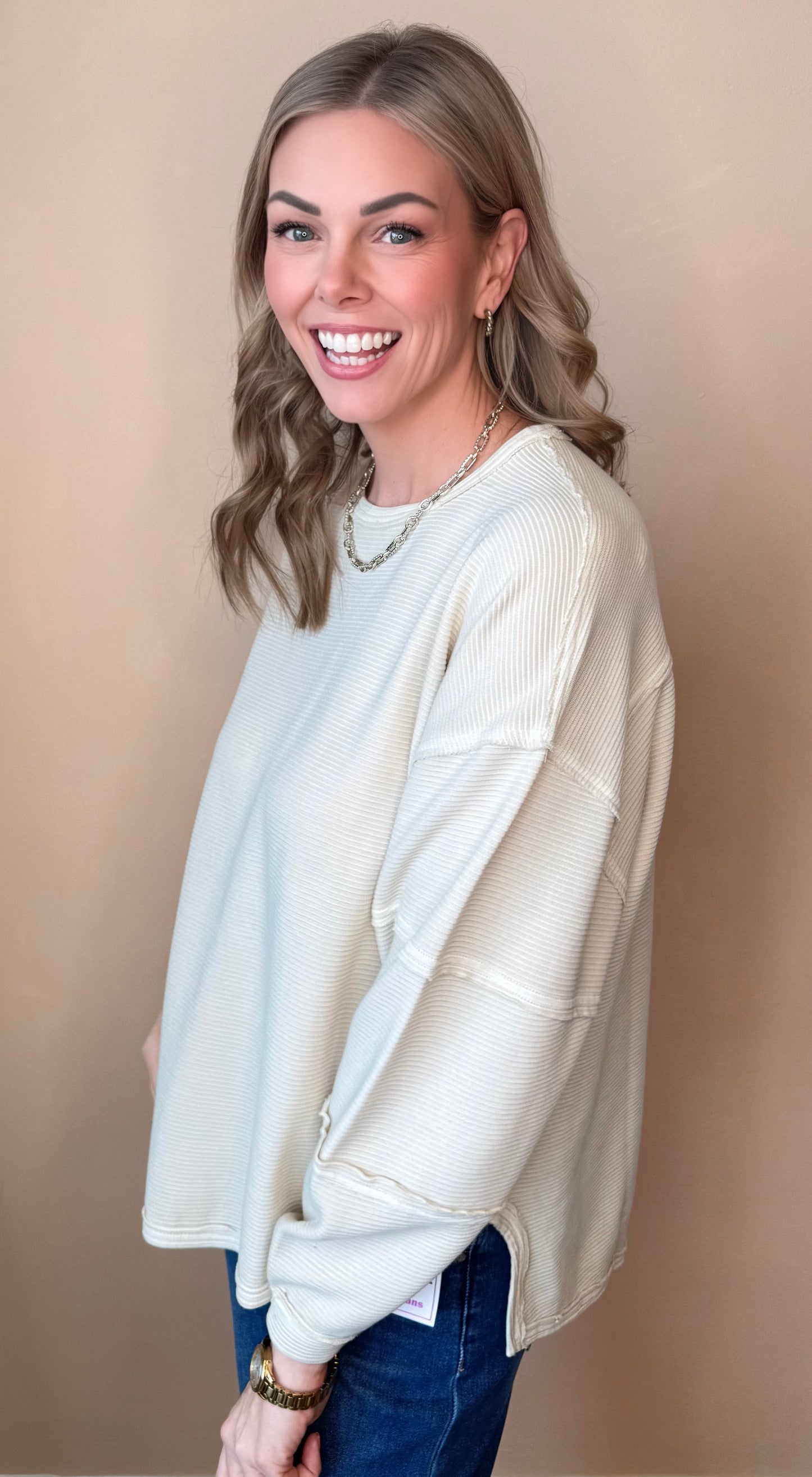 Woman wearing a cream cardigan over a light blue top on a beige background