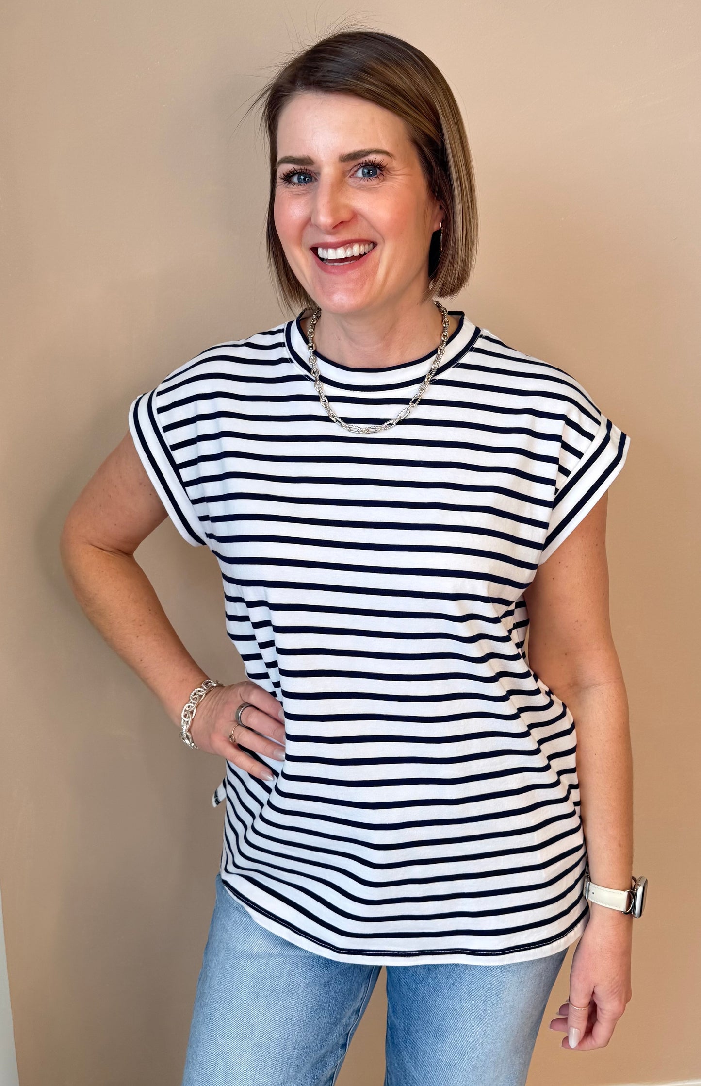 Woman wearing a black and white striped shirt against a beige wall